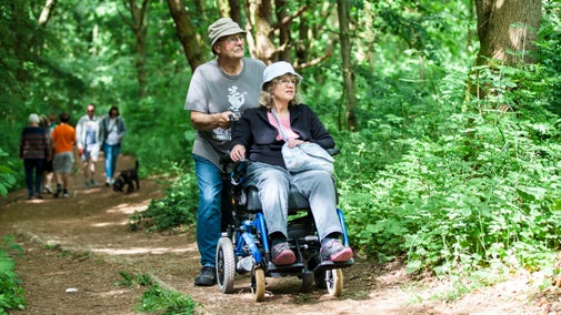 Visitors exploring the accessible footpath at Foremark, Derbyshire in woodland surrounded by trees